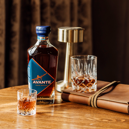 Avante Brandy VSOP Bottle on Table surrounded by crystal tumblers.