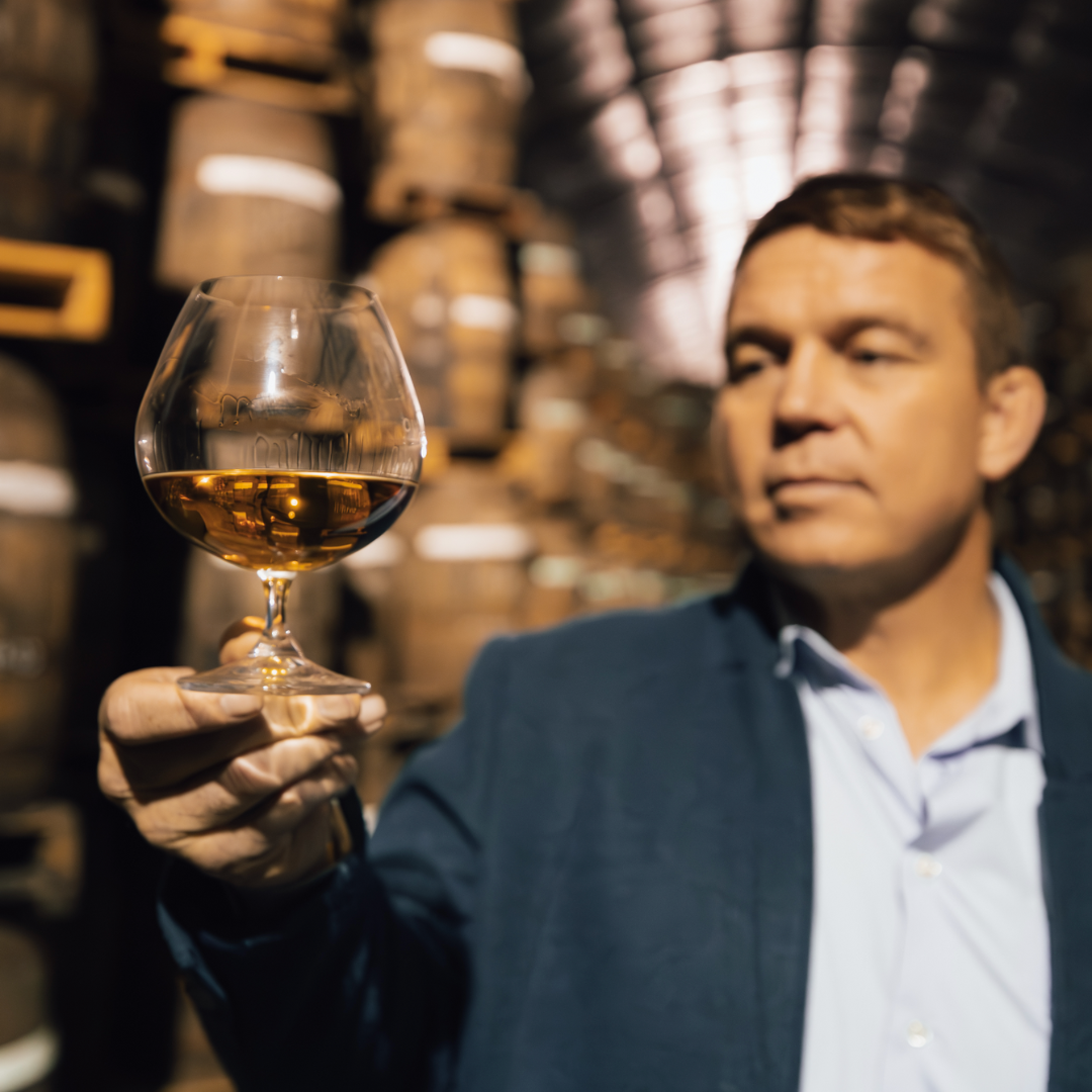 John Smit holding Avante Brandy VSOP Glass in amongst Cape Brandy Barrels.